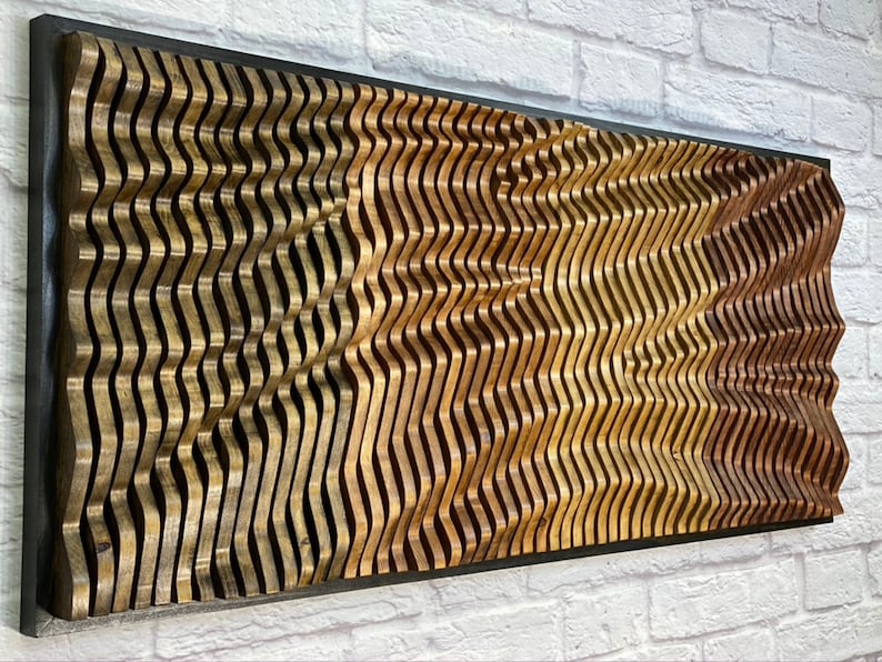 May include: A wall sculpture made of wood with a wavy pattern. The wood is stained in shades of brown, gold, and red. The sculpture is framed in black.