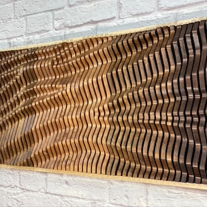 May include: A large wooden wall art piece made of multiple curved pieces of wood in shades of brown. The wood is arranged in a wave pattern, creating a 3D effect.