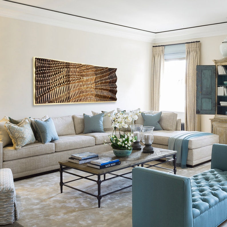 May include: A modern living room with a large sectional sofa in beige fabric, a coffee table with books and a vase of white flowers, and a large abstract wall art piece in brown and gold tones.