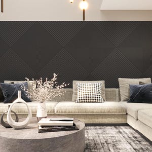 Könnte beinhalten: Ein großes Ecksofa mit beigefarbener Polsterung und einer dunkelgrauen geometrischen Musterwand dahinter. Das Sofa hat mehrere Kissen, darunter ein schwarz-weiß gemustertes Kissen. Auf dem Couchtisch vor dem Sofa stehen zwei weiße Keramikvasen.