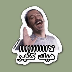 May include: A white sticker with a cartoon image of a man laughing and waving. The sticker has Arabic text and numbers. The background is a solid olive green color.
