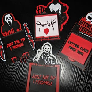 May include: A collection of horror-themed 3D-printed items, including a Ghostface mask, a knife, and a Pennywise the Clown design. The items feature the text "JUST THE TIP I PROMISE" and "CUTTING CLASS SINCE 1980" in red and black.