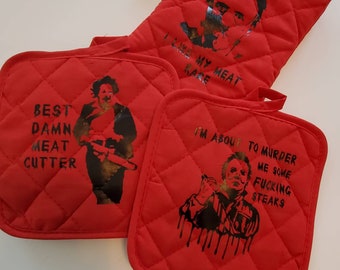 May include: Set of three red quilted pot holders with black and white graphic prints of a horror movie character. The pot holders have the text "Best Damn Meat Cutter", "I Like My Meat Rare", and "I'm About To Murder Me Some Fucking Steaks".