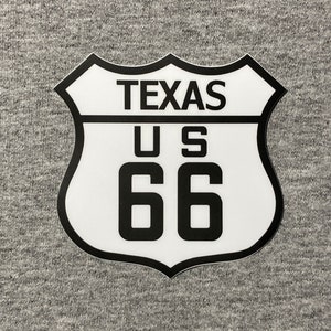 May include: White and black US Route 66 sign with the word "TEXAS" above the number "66".