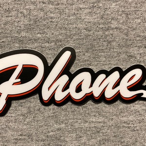 May include: A black and white sticker with the word "Phone" in a white, stylized font with a red outline. The sticker is on a gray surface.