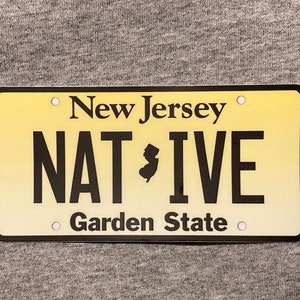 Pu&ograve; includere: Targa rettangolare con sfondo sfumato giallo. Le parole "New Jersey" e "Garden State" sono stampate in nero. La parola "NATIVE" &egrave; anch'essa stampata in nero, con un contorno nero dello stato del New Jersey al centro.
