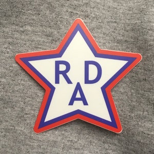May include: A red and blue star-shaped sticker with the letters "RDA" in blue on a white background.