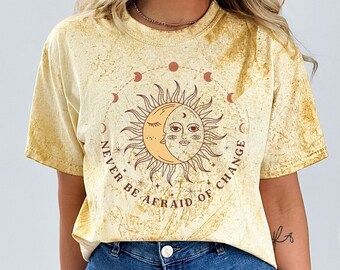May include: A yellow tie-dye t-shirt with a graphic of a sun and moon with the text "Never be afraid of change".