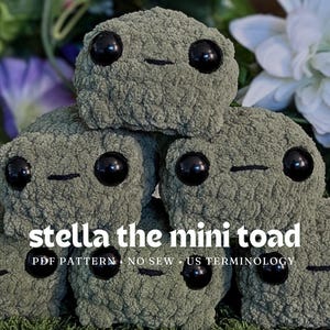 May include: A stack of five sage green crocheted toad figures with large black plastic eyes and embroidered mouths. The text "stella the mini toad" and "PDF PATTERN • NO SEW • US TERMINOLOGY" is overlaid in white on the center of the plush figures.
