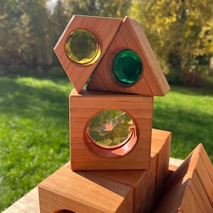 May include: Wooden blocks with colorful, clear, geometric shapes in the center of each block. The blocks are stacked on top of each other.