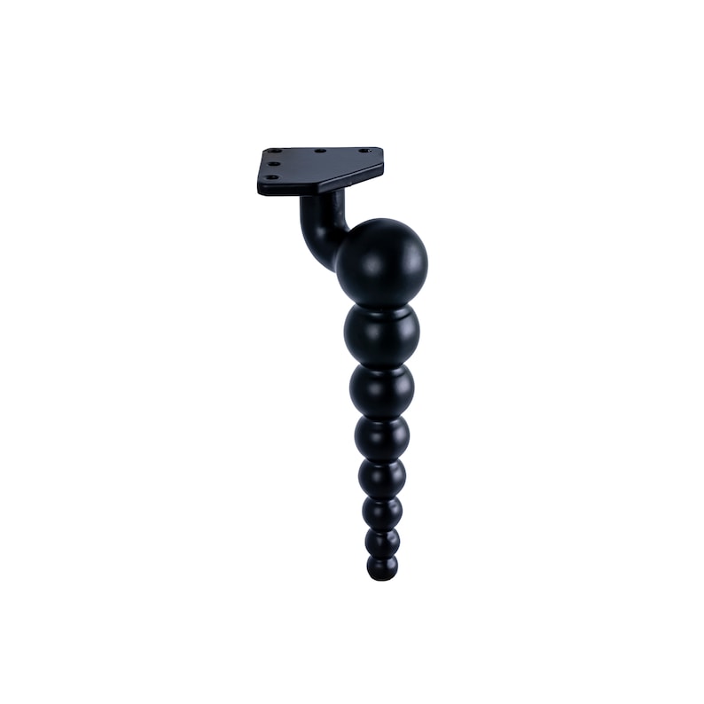May include: Black metal furniture leg with a rounded, beaded design. The leg has a flat, triangular base with mounting holes.
