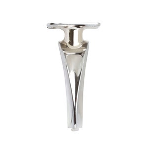 Può includere: Una gamba per mobili in metallo argentato con un design curvo. La gamba ha una parte superiore piatta con un foro al centro.