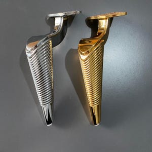 May include: Two decorative furniture legs, one silver and one gold, with a textured, ribbed design.