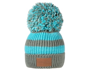 May include: A grey and blue striped knitted beanie with a large fluffy pom pom on top. The beanie has a brown leather patch with the word "wimble" on it.