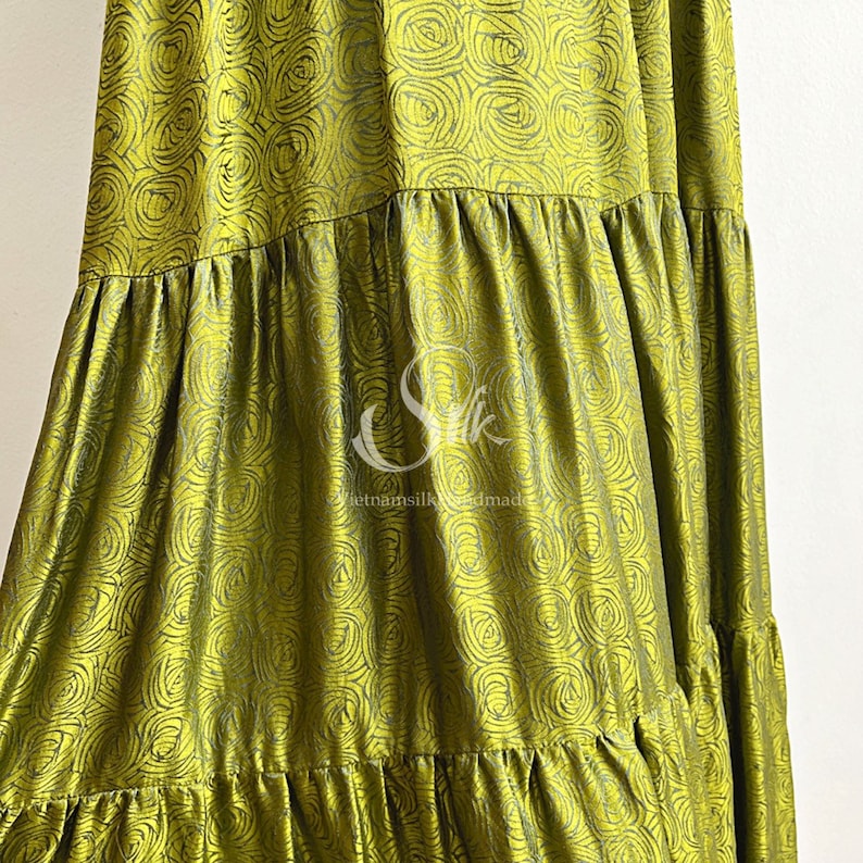May include: A green silk skirt with a floral pattern. The skirt has multiple tiers and is made in Vietnam.
