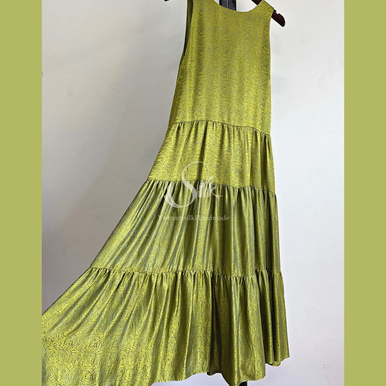 May include: A tiered maxi dress in a vibrant green color with a floral pattern. The dress is sleeveless and has a relaxed fit.