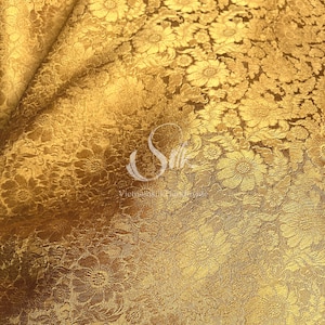 以下が含まれることがあります： 花柄の金色の生地。生地は、質感があり、ほぼ金属のような外観です。