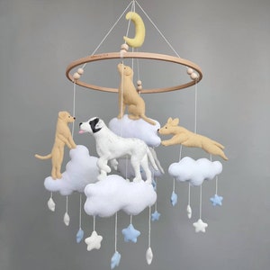 May include: A wooden baby mobile with a yellow crescent moon, four felt dogs, and white clouds with blue stars hanging from it.