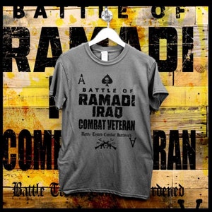 May include: A gray t-shirt with a black graphic design that says "Battle of Ramadi Iraq Combat Veteran" with a spade card and the letter A on either side. The text "Battle Tested Combat Hardened" is below the main text.
