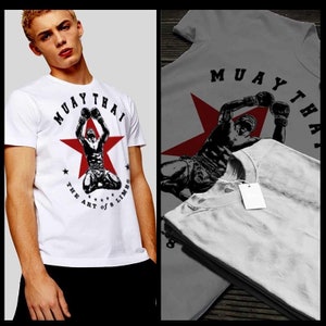 May include: White t-shirt with a red star and a black and white illustration of a person in a fighting pose. The text "Muay Thai The Art of 8 Limbs" is printed on the shirt.