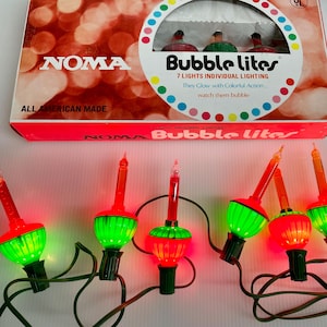 May include: A set of NOMA Bubble Lites Christmas lights. The lights have red and green bulbs with a bubble effect. The box reads "7 LIGHTS INDIVIDUAL LIGHTING" and "ALL AMERICAN MADE".