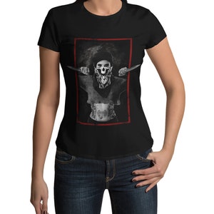May include: Black t-shirt with a graphic of a woman wearing a skull bandana and holding two knives. The graphic is framed in a red border.