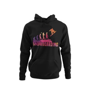 Könnte beinhalten: Schwarzer Hoodie mit einem Grafikdruck, der die Evolution des Snowboardens zeigt. Die Grafik zeigt eine Reihe von Strichmännchen, die sich von einem Höhlenmenschen zu einem modernen Snowboarder entwickeln. Der Text "SNOWBOARDING" ist unter der Grafik gedruckt.