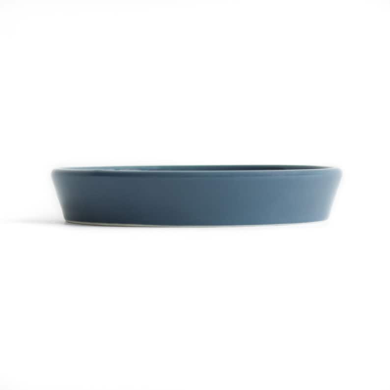 May include: A round, blue ceramic dish with a slightly raised rim.