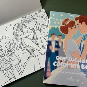 Może przedstawiać: Książka do kolorowania z parą ślubną na okładce. Okładka jest niebieska z białymi płatkami śniegu i tekstem "Our Wedding Coloring Book" w kolorze białym. Tekst pod tytułem brzmi "Capture your memories, create your story." Książka jest otwarta na stronie z czarno-białą ilustracją weselnego przyjęcia.