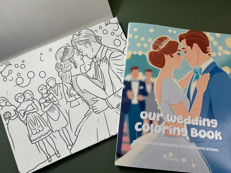 Może przedstawiać: Książka do kolorowania z parą ślubną na okładce. Okładka jest niebieska z białymi płatkami śniegu i tekstem "Our Wedding Coloring Book" w kolorze białym. Tekst pod tytułem brzmi "Capture your memories, create your story." Książka jest otwarta na stronie z czarno-białą ilustracją weselnego przyjęcia.