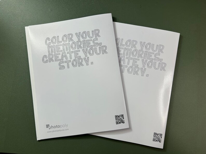 Może przedstawiać: Dwa puste białe albumy fotograficzne z tekstem "COLOR YOUR MEMORIES, CREATE YOUR STORY." nadrukowanym na okładce. Tekst jest w stylizowanym kroju pisma. Albumy mają kod QR na tylnej stronie.