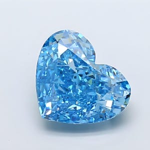 Puede incluir: Una piedra preciosa en forma de corazón de color azul claro vibrante con una superficie facetada que crea múltiples ángulos reflectantes. La piedra presenta una base puntiaguda y una parte superior redondeada con corte brillante.