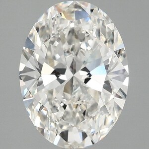 Puede incluir: Un diamante incoloro y transparente de talla oval con una superficie de facetas brillantes. La piedra preciosa muestra numerosas facetas triangulares y en forma de cometa que reflejan la luz, creando un patrón de alto contraste.