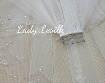 May include: White bridal veil with a beaded edge and a comb for attaching to hair. The veil is layered and has a sheer, delicate texture.