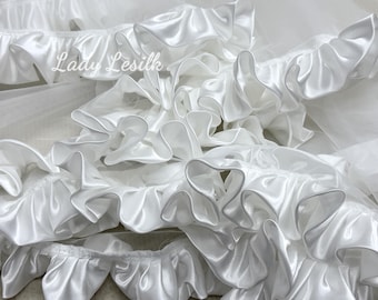 May include: White satin ruffle trim with a soft, flowing texture. The trim is perfect for adding a touch of elegance to any project.