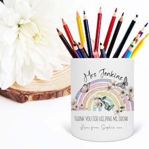 May include: White ceramic pencil holder with a rainbow design, flowers, and butterflies. The text "Mrs Jenkins, Thank you for helping me grow, Love from Sophie xxx" is printed on the holder.