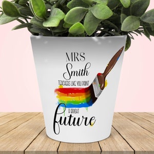 May include: White ceramic planter with a rainbow paintbrush design and the text "MRS Smith TEACHERS LIKE YOU PAINT A BRIGHT future".