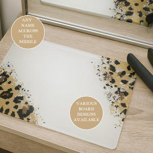 May include: A rectangular cutting board with a white centre and leopard print accents. The board has the text "ANY NAME ACROSS THE MIDDLE" and "VARIOUS BOARD DESIGNS AVAILABLE" in circular text.