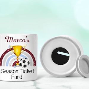 May include: White ceramic money box with a slot on top. The box has a colourful design with a rainbow, a football, a trophy, and the text "Marco's Season Ticket Fund".