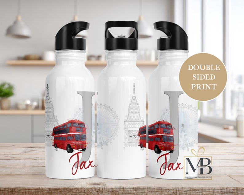 May include: Three white metal water bottles with black lids featuring a London theme. The design includes a red double-decker bus, a grey sketch of Big Ben and the London Eye, a large grey letter J, and the name Jax in red script text.