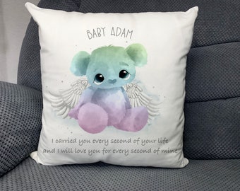 May include: A white pillow with a watercolor illustration of a rainbow colored teddy bear with angel wings. The text "BABY ADAM" is at the top of the pillow. The text "I carried you every second of your life and I will love you for every second of mine" is at the bottom of the pillow.
