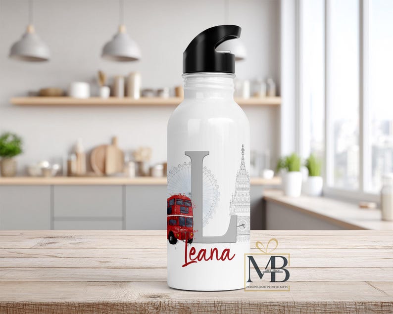 May include: A white water bottle with a black lid featuring a large gray letter L, a red double-decker bus, a gray Ferris wheel, and a gray clock tower illustration. The name Leana is printed in red script below the letter L on the bottle.