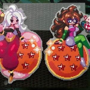 May include: Two pixel art figures of female characters with long hair, one with white hair and the other with brown hair, sitting on orange and yellow dragon balls with red stars. Both figures are holding a dessert in their hands.