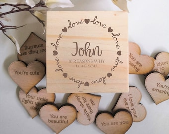 May include: A wooden box with a heart-shaped lid that says "John 10 Reasons Why I Love You..." on the front. The box is surrounded by small wooden hearts with different messages on them, such as "You're cute", "You are caring", and "Your smile lights up my day".