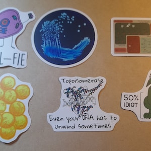 May include: A set of six stickers featuring humorous science-themed illustrations. The stickers include a cell taking a selfie, a petri dish with bacteria, a diagram of a DNA molecule, a cluster of yellow cells, a cartoon dragon, and a cartoon DNA molecule with the text "Topoisomerase Even your DNA has to unwind sometimes".