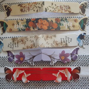 May include: Set of six colorful bookmarks featuring butterflies and floral designs. Each bookmark has a different design and includes a quote about love. The bookmarks are made of sturdy cardstock and are perfect for marking your place in a book.