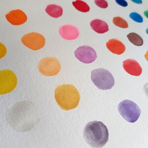 May include: A white background with a diagonal row of colorful watercolor dots. The dots are arranged in a rainbow pattern, starting with red and ending with purple.