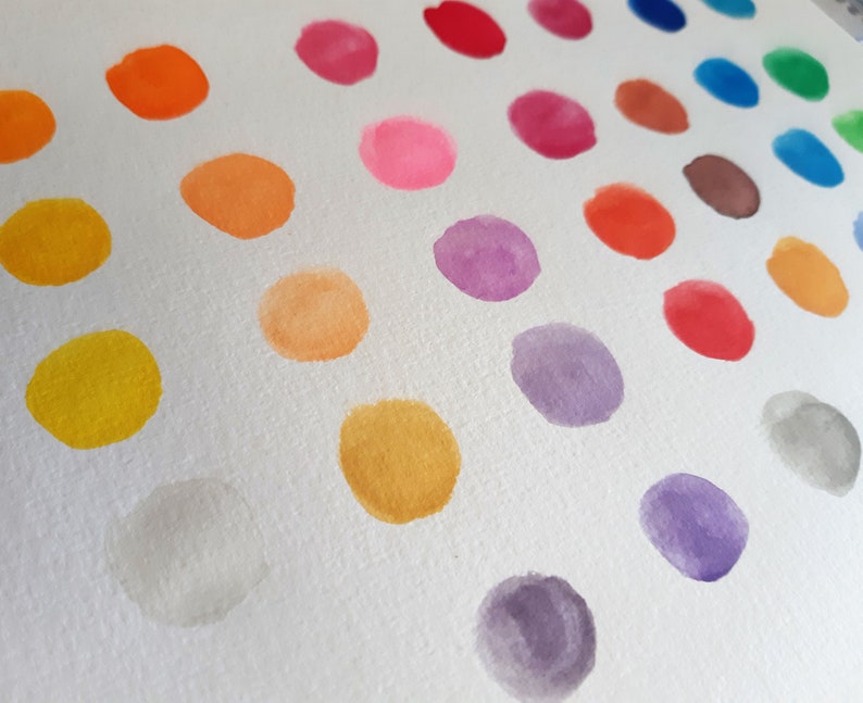 May include: A white background with a diagonal row of colorful watercolor dots. The dots are arranged in a rainbow pattern, starting with red and ending with purple.