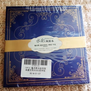 K&ouml;nnte beinhalten: Ein blaues Aquarell-Skizzenbuch mit goldenen Akzenten und dem Text "Watercolour 水彩风琴本 鲁本斯(星空系列)/棉浆/中紋 14cm x 14cm(合)140cmx14cm(展开) Cotton/300gsm/Cold pressed 0110001070 14*14 鲁本斯水彩风琴本星空系列300克中纹 B2-A-01-07" auf dem Einband.