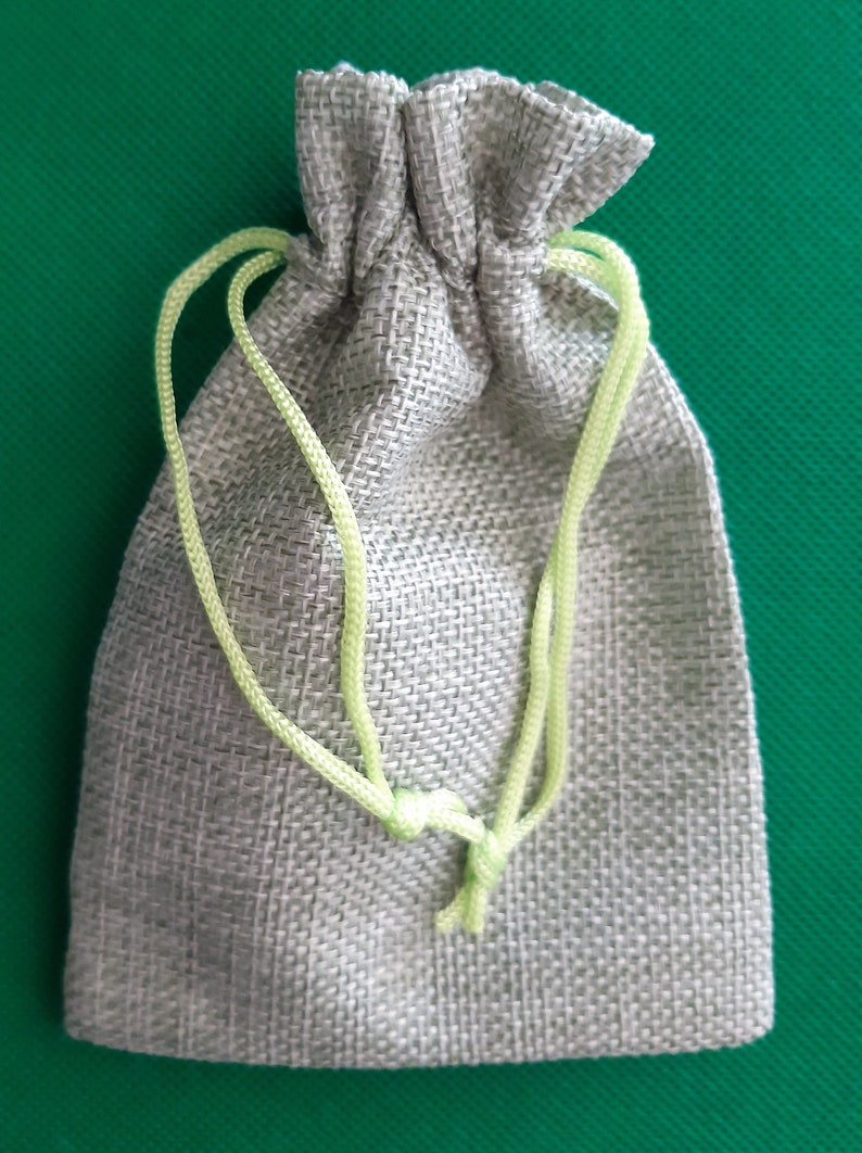 May include: A small, light gray drawstring bag made of burlap with a light green drawstring.